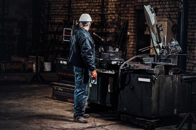 Un trabajador experimentado está trabajando en una fábrica de metal usando una máquina herramienta especial.