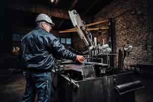 Foto gratuita un trabajador experimentado está trabajando en una fábrica de metal usando una máquina herramienta especial.
