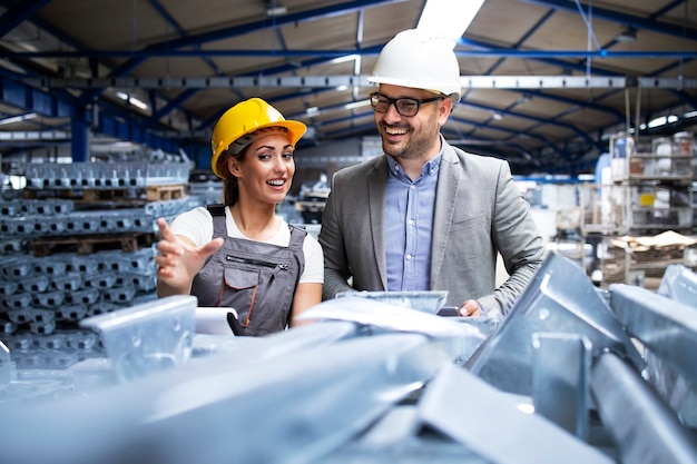 Foto gratuita trabajador de fábrica con casco y uniforme mostrando nuevos productos metálicos al supervisor gerente