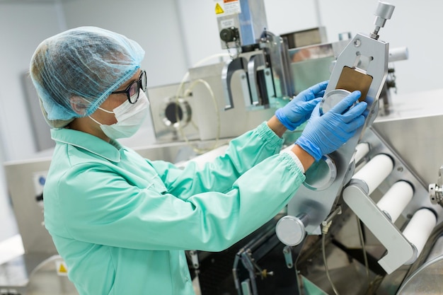 Trabajador de una fábrica caucásica con traje de laboratorio azul, compruebe las lecturas de la máquina de fabricación