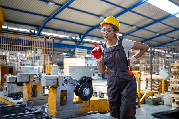 Trabajador de la fábrica femenina que opera la máquina industrial en la línea de producción