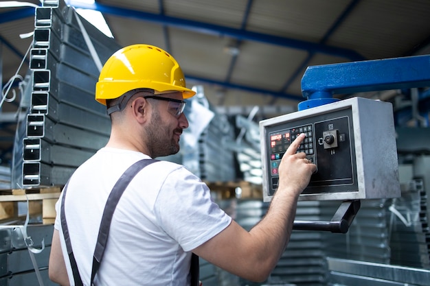 Trabajador de fábrica operando una máquina industrial y estableciendo parámetros en la computadora