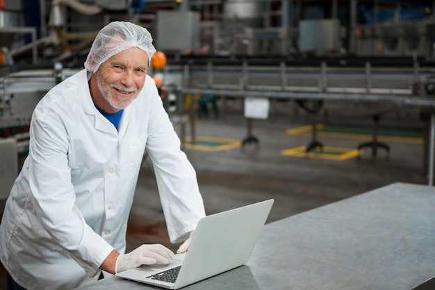 Trabajador feliz usando laptop en la fábrica.