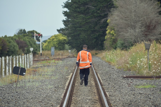 Foto gratuita trabajador del ferrocarril caminando entre las vías del tren