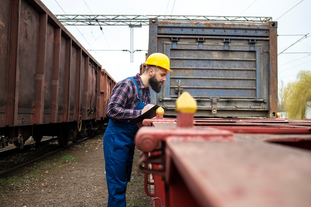 Trabajador del ferrocarril comprobando los vagones de tren en la estación