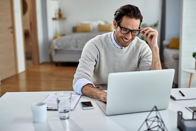 Trabajador independiente feliz que usa la computadora mientras trabaja en casa