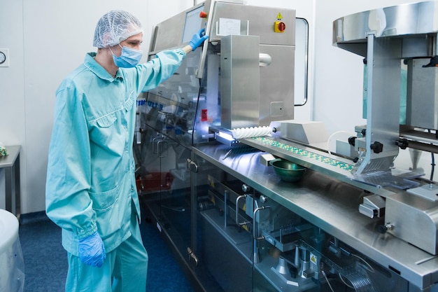 Trabajador de la industria farmacéutica. Trabajador en ropa de protección. Producción de tabletas en condiciones de trabajo estériles.