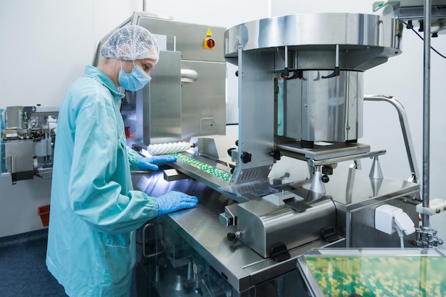 Trabajador de la industria farmacéutica. Trabajador en ropa de protección. Producción de tabletas en condiciones de trabajo estériles.