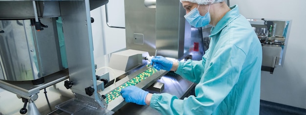 Trabajador de la industria farmacéutica. Trabajador en ropa de protección. Producción de tabletas en condiciones de trabajo estériles.