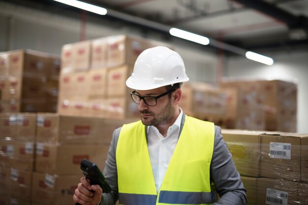 Trabajador industrial con escáner de código de barras haciendo un seguimiento y controlando las mercancías que llegan al almacén