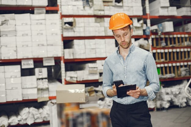 Trabajador industrial en el interior de la fábrica. Hombre de negocios con casco naranja. Hombre con camisa azul.