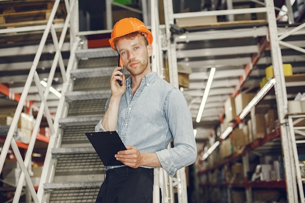 Trabajador industrial en el interior de la fábrica. Hombre de negocios con casco naranja. Hombre con camisa azul.