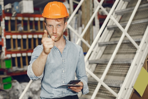 Trabajador industrial en el interior de la fábrica. Hombre de negocios con casco naranja. Hombre con camisa azul.