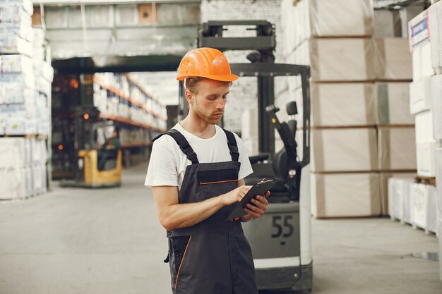 Trabajador industrial en el interior de la fábrica. Joven técnico con casco naranja.