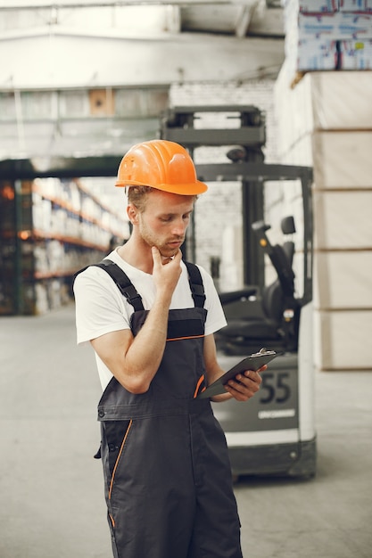 Trabajador industrial en el interior de la fábrica. Joven técnico con casco naranja.