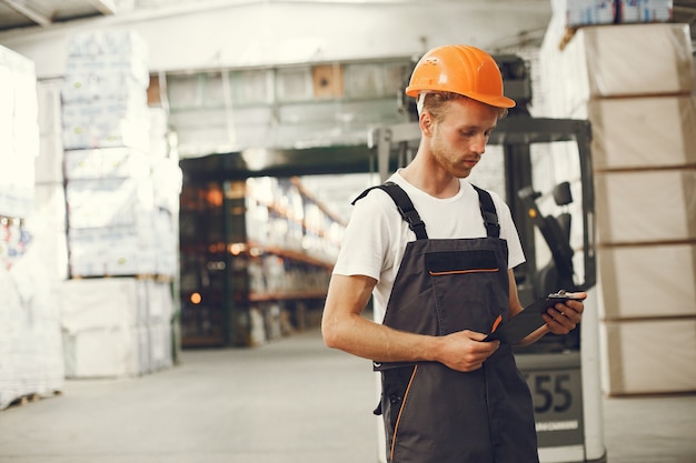 Trabajador industrial en el interior de la fábrica. Joven técnico con casco naranja.