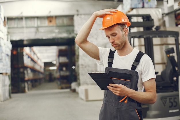 Trabajador industrial en el interior de la fábrica. Joven técnico con casco naranja.