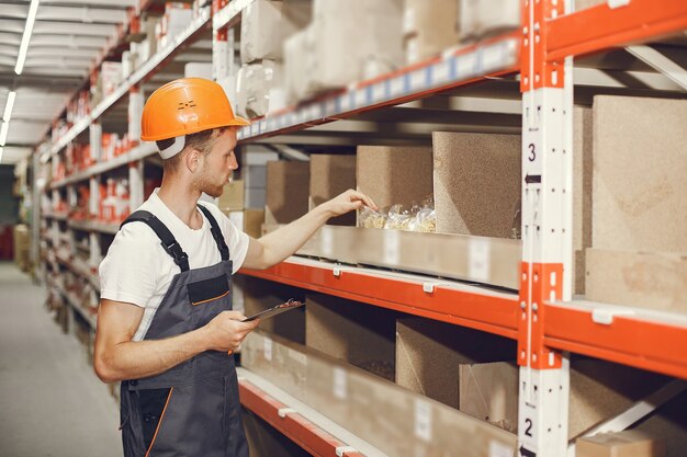 Trabajador industrial en el interior de la fábrica. Joven técnico con casco naranja.