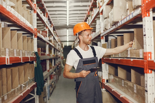 Trabajador industrial en el interior de la fábrica. Joven técnico con casco naranja.