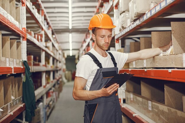 Trabajador industrial en el interior de la fábrica. Joven técnico con casco naranja.