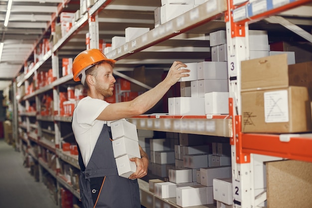 Trabajador industrial en el interior de la fábrica. Joven técnico con casco naranja.