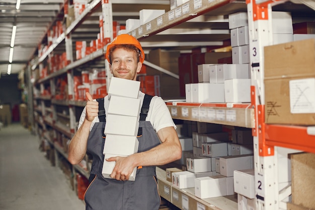 Trabajador industrial en el interior de la fábrica. Joven técnico con casco naranja.