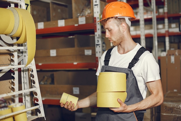 Trabajador industrial en el interior de la fábrica. Joven técnico con casco naranja.