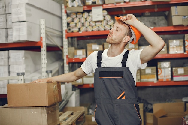 Trabajador industrial en el interior de la fábrica. Joven técnico con casco naranja.