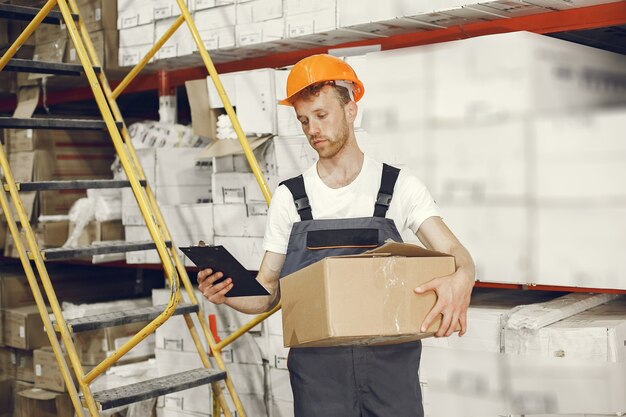 Trabajador industrial en el interior de la fábrica. Joven técnico con casco naranja.