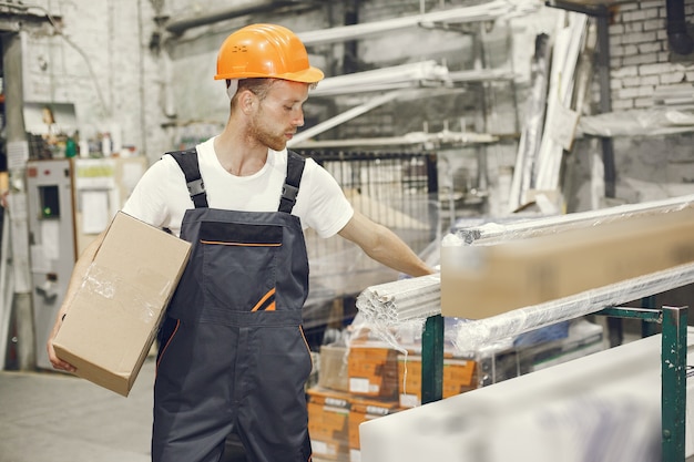 Trabajador industrial en el interior de la fábrica. Joven técnico con casco naranja.