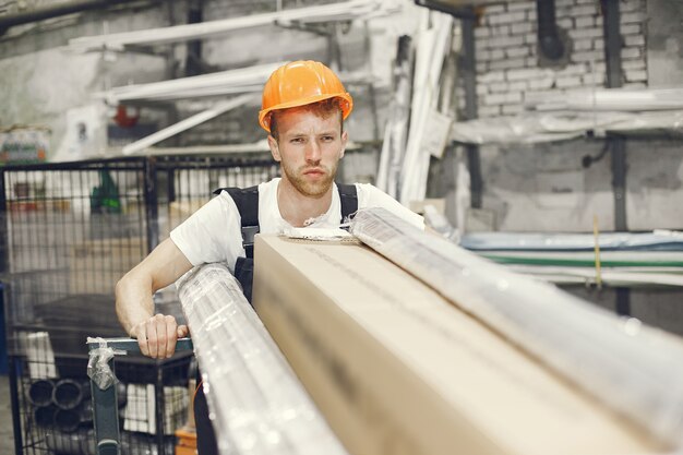 Trabajador industrial en el interior de la fábrica. Joven técnico con casco naranja.