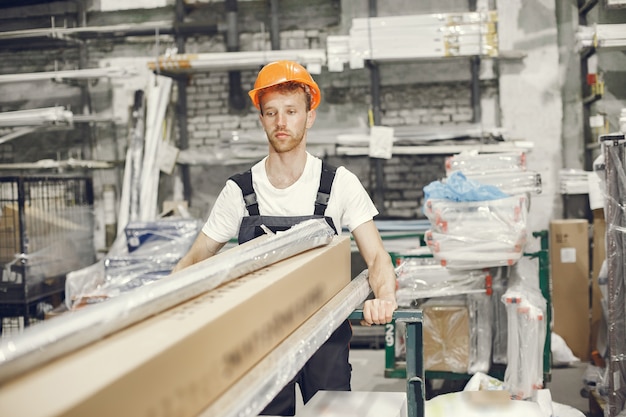 Trabajador industrial en el interior de la fábrica. Joven técnico con casco naranja.