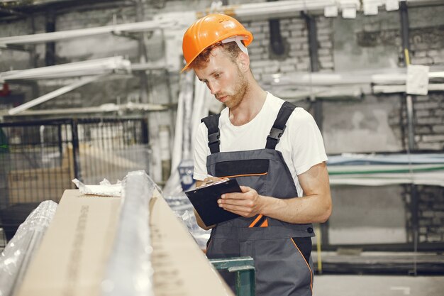 Trabajador industrial en el interior de la fábrica. Joven técnico con casco naranja.