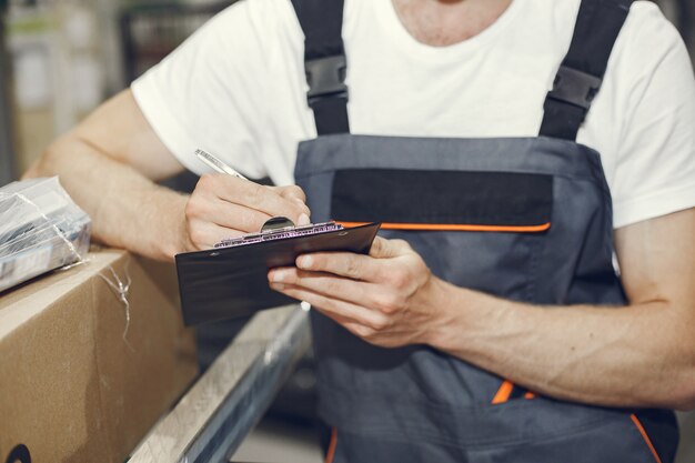 Trabajador industrial en el interior de la fábrica. Joven técnico con casco naranja.