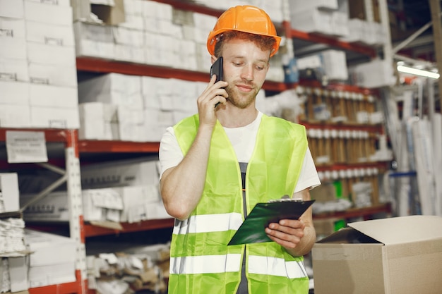 Trabajador industrial en el interior de la fábrica. Joven técnico con casco naranja.