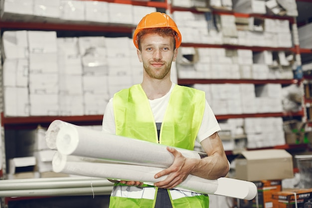 Trabajador industrial en el interior de la fábrica. Joven técnico con casco naranja.