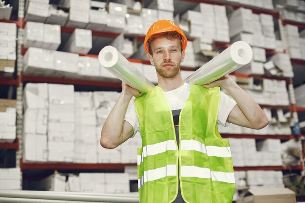 Trabajador industrial en el interior de la fábrica. Joven técnico con casco naranja.