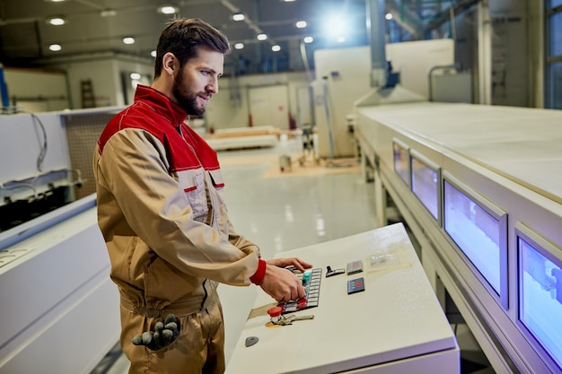 Foto gratuita trabajador industrial que opera una máquina automatizada para el procesamiento de madera en una fábrica.