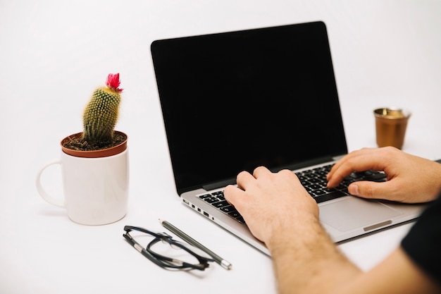 Foto gratuita trabajador irreconocible escribiendo en la computadora portátil