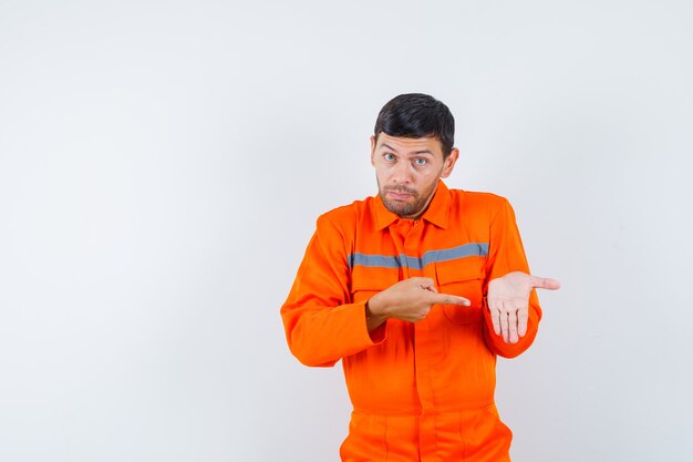 Trabajador joven apuntando a su palma vacía en uniforme.