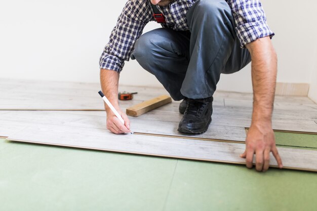 Trabajador joven que recubre un piso con tablas de piso laminado