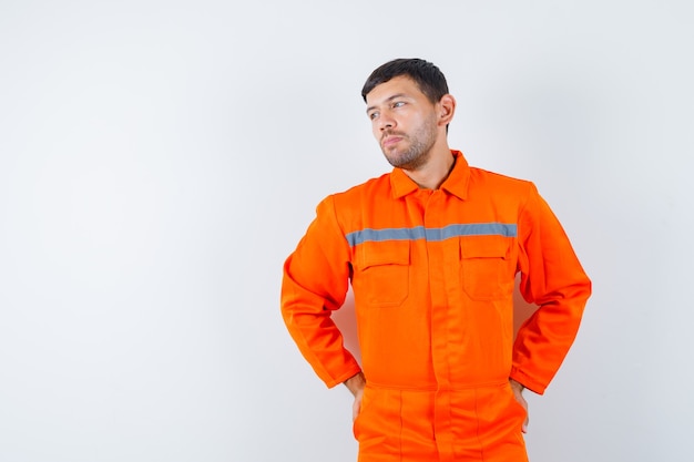 Foto gratuita trabajador joven en uniforme mirando a un lado y mirando pensativo.