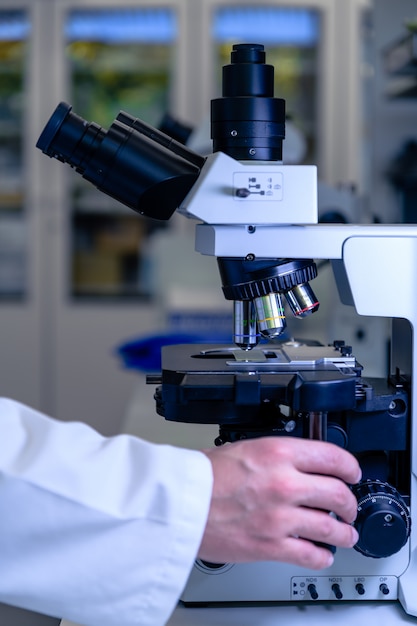 Un trabajador de laboratorio que trabaja con un microscopio moderno mientras realiza una investigación.