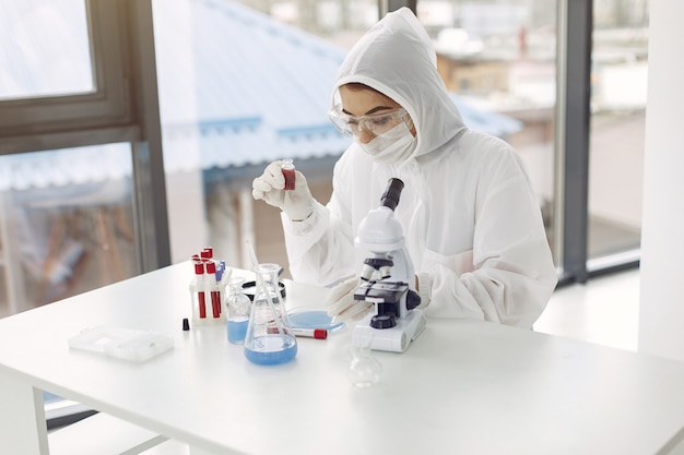 Trabajador de laboratorio en traje de overol está ajustando el microscopio