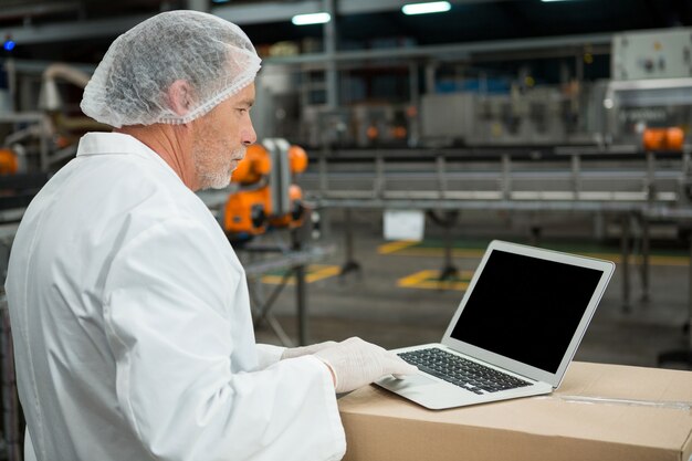 Trabajador masculino con laptop en la fábrica.