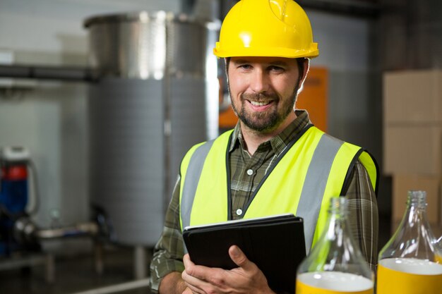 Trabajador masculino sonriente sosteniendo tableta digital en la fábrica.