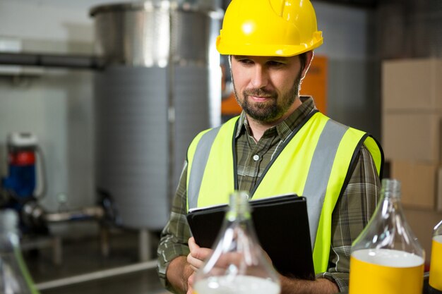 Trabajador masculino mediante tableta digital en la fábrica.