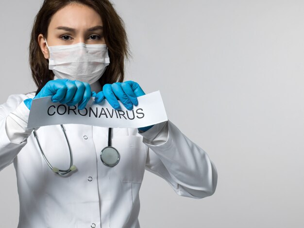 Foto gratuita trabajador médico destrozando coronavirus escrito hoja de papel