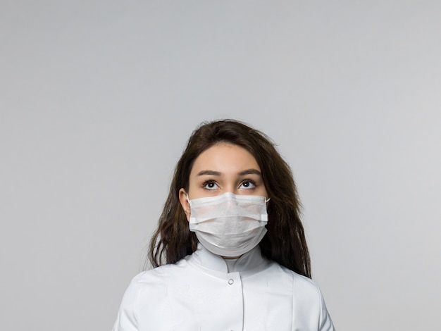 Trabajador médico mirando a distancia en uniforme médico blanco y máscara protectora blanca