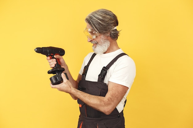 Trabajador en mono. Hombre con herramientas. Senior con destornillador.